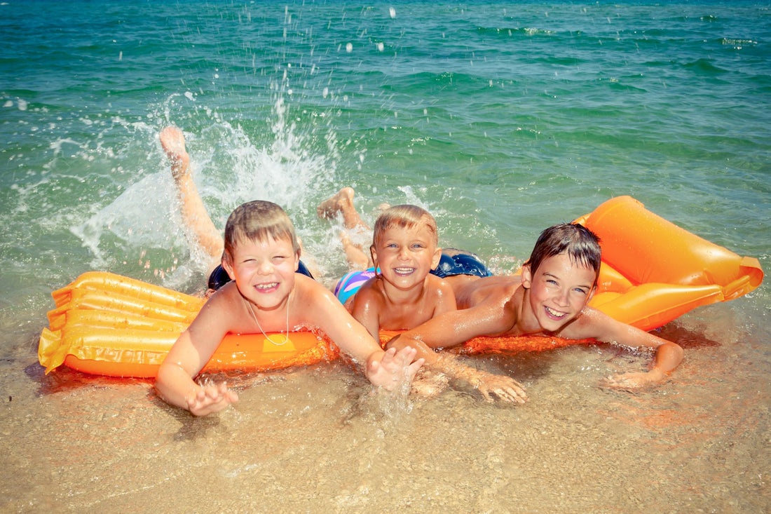 3 boys lying on their blow-up mattress on the beach in Australia